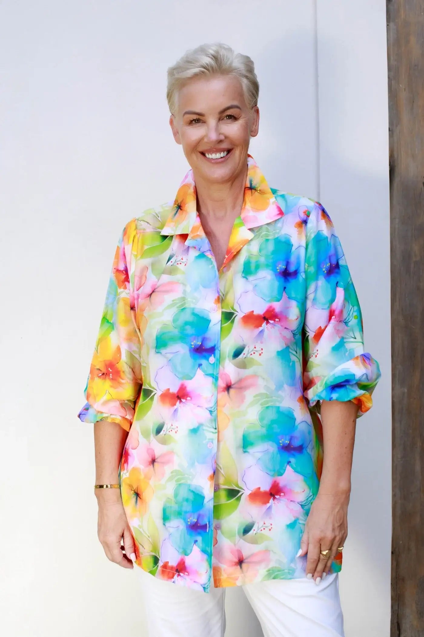 Smiling woman wearing a colorful floral shirt from Claire Powell, styled for relaxed elegance.