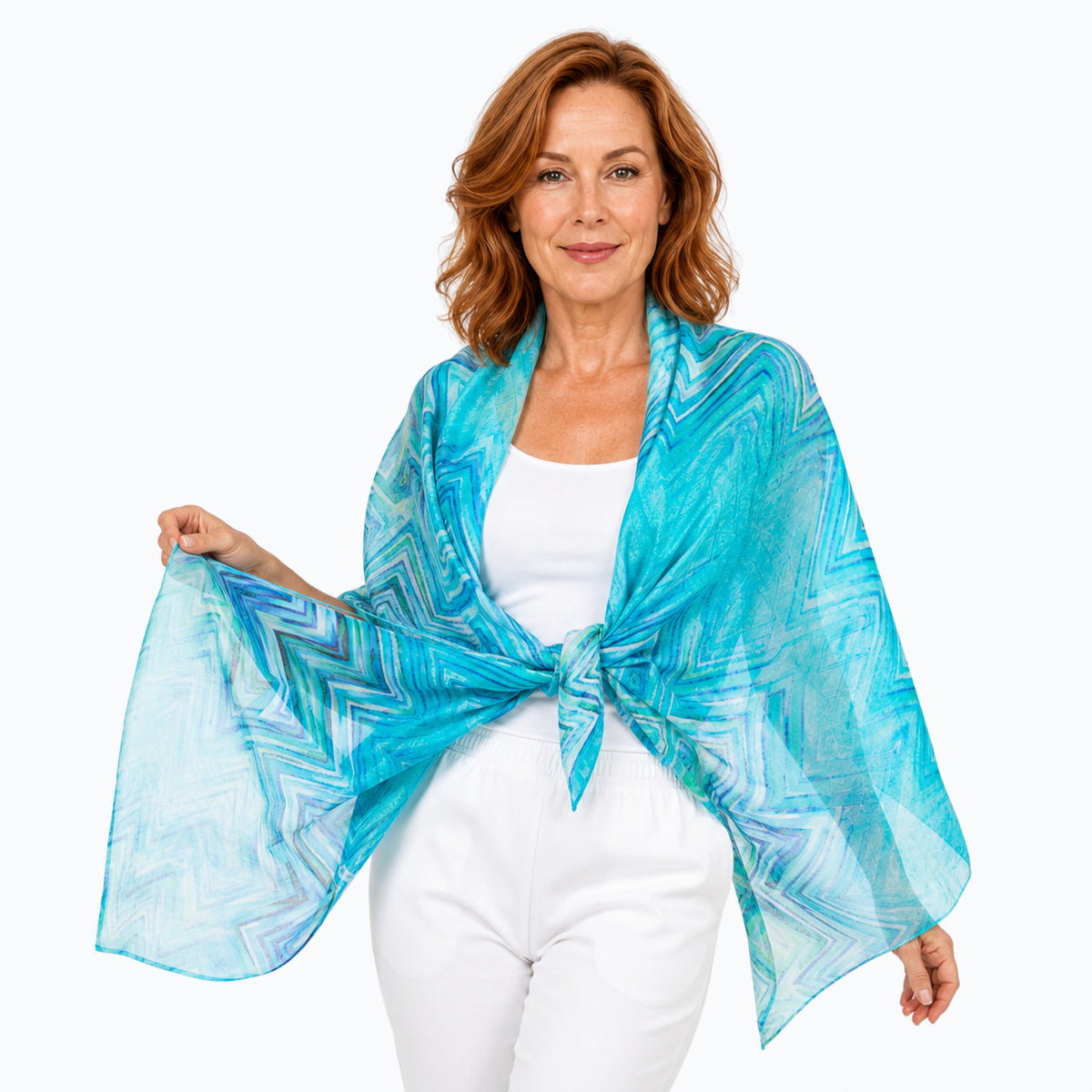Woman wearing the Claire Powell Serenity silk scarf tied as a shawl over a white camisole and white capris, close front view