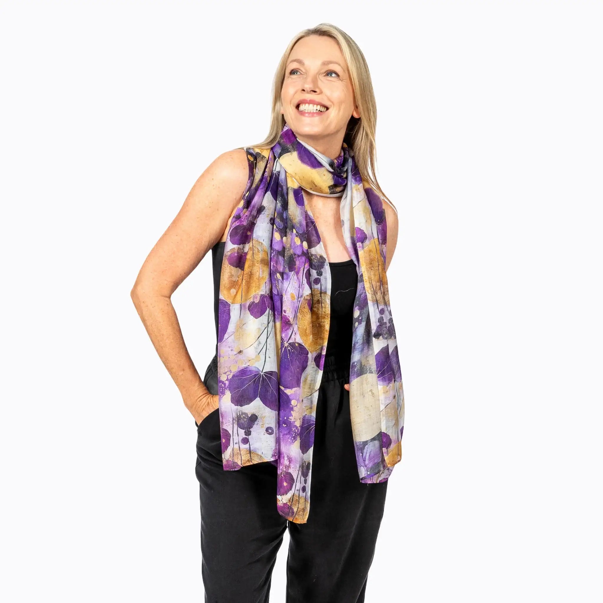 Woman wearing a colorful purple and gold leaf print scarf from Claire Powell over a black top