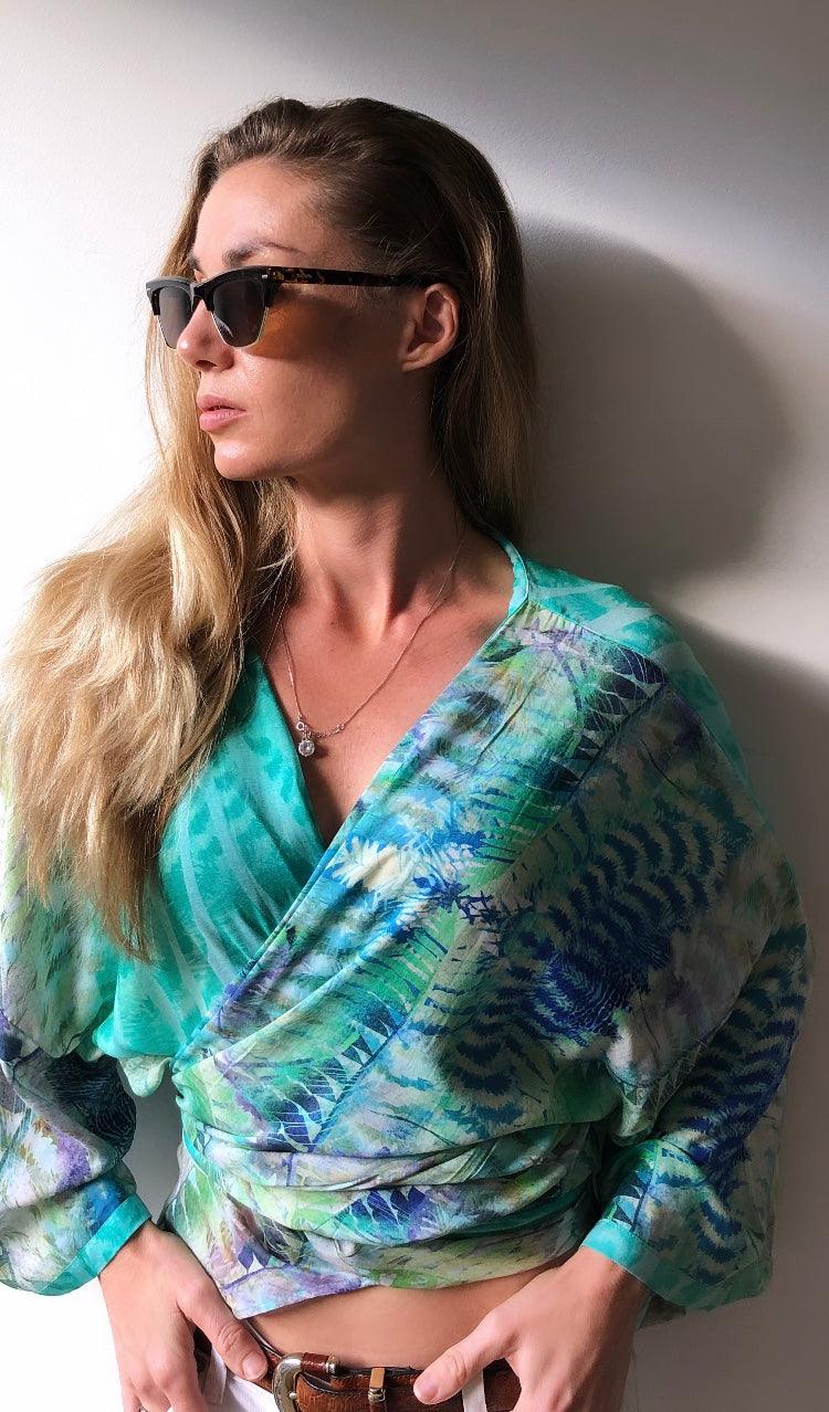 Woman in stylish green and blue patterned wrap top by Claire Powell, wearing sunglasses