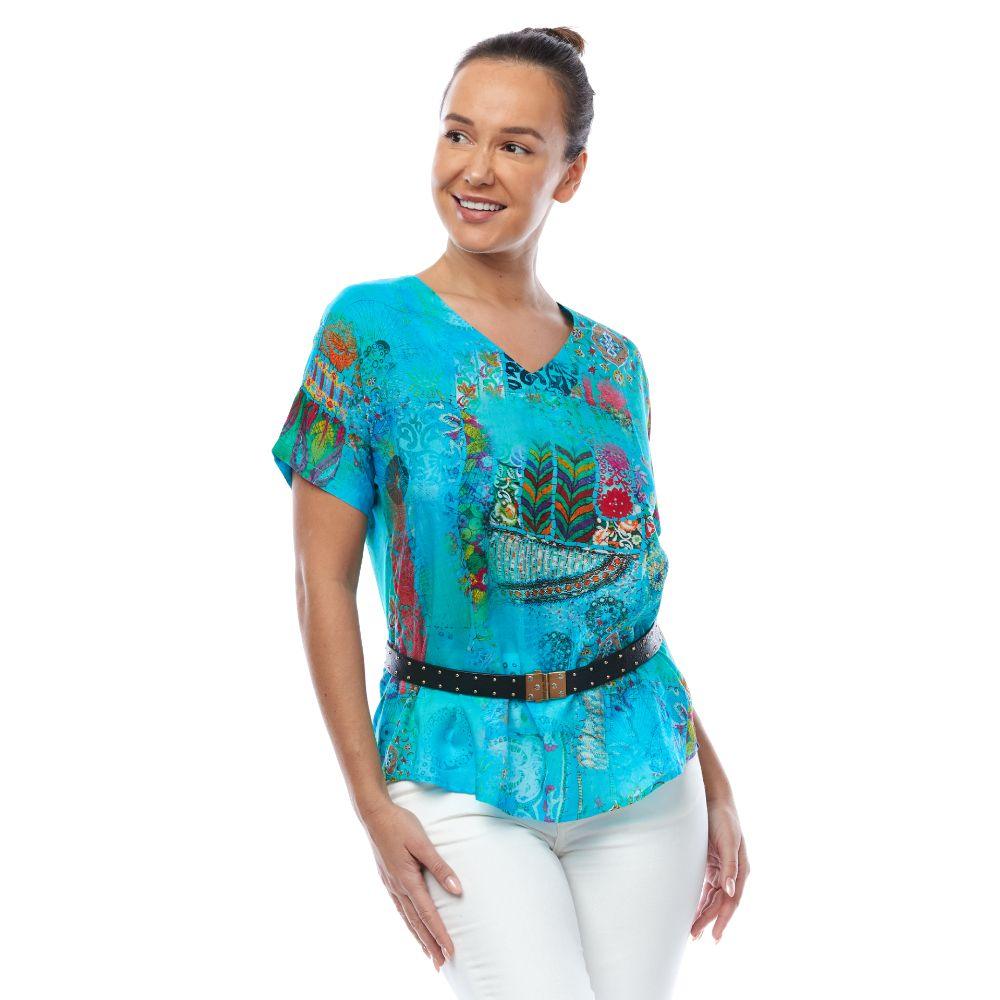 Woman wearing a vibrant blue patterned Claire Powell top with a black belt and white pants