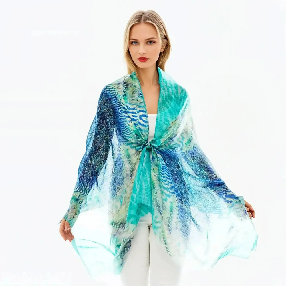 Woman wearing Claire Powell silk marine scarf in blue and aqua, styled over white outfit