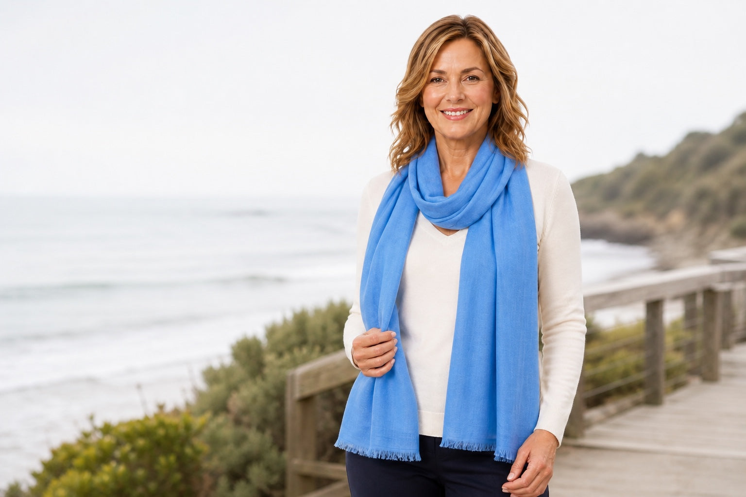 Woman wearing the Denim Blue silk wool scarf on a coastal boardwalk