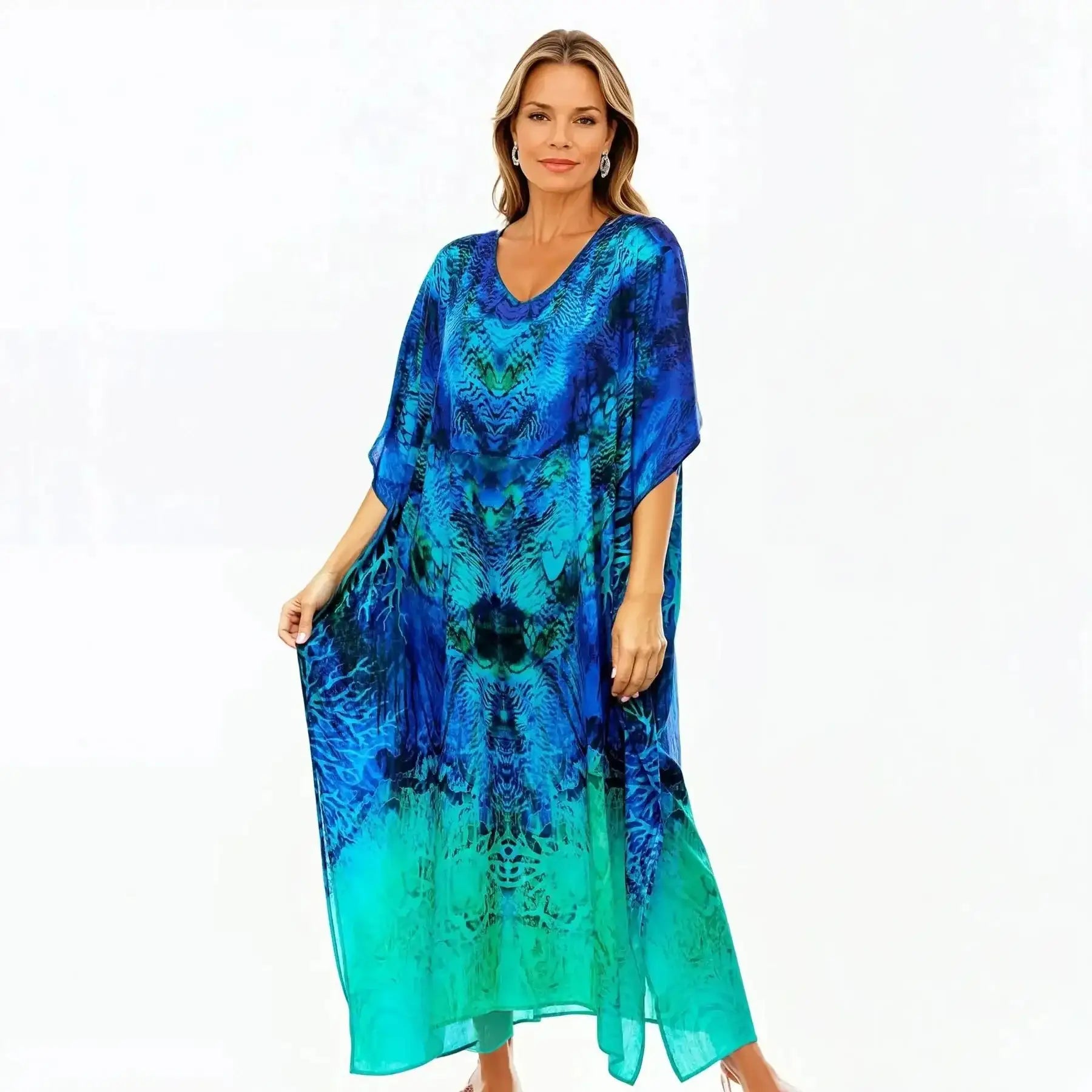 Woman wearing blue and turquoise kaftan dress from Claire Powell, standing against white background