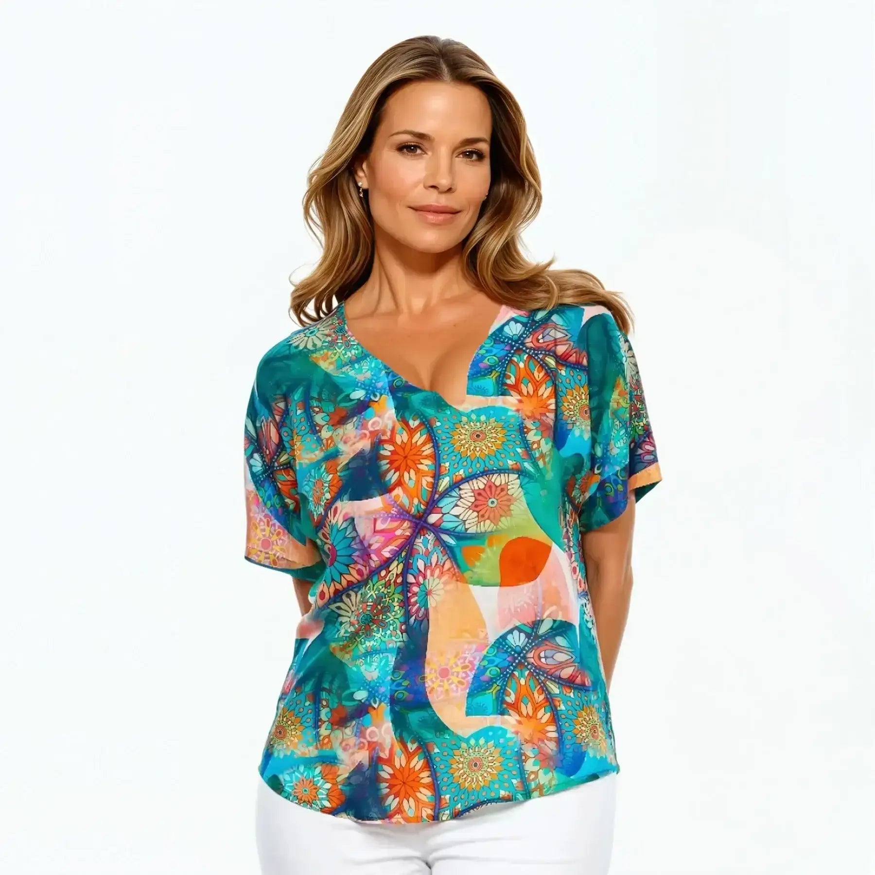 Woman wearing a colorful floral V-neck t-shirt by Claire Powell, styled with white pants