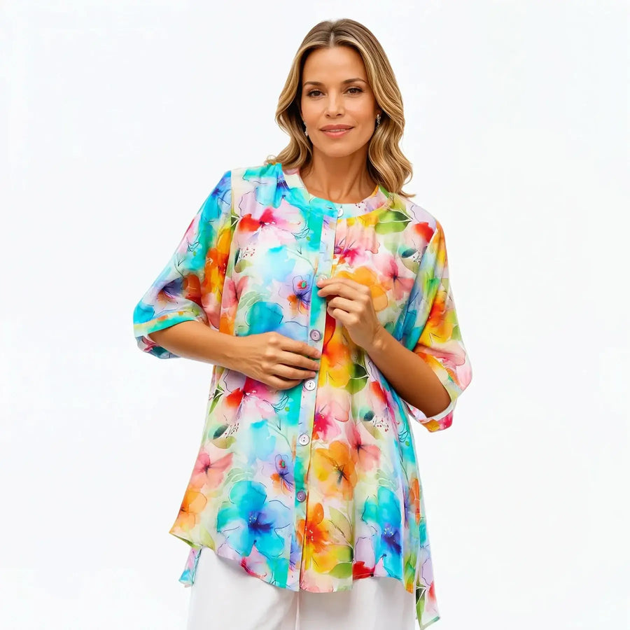 Woman wearing a colorful floral A-line tunic blouse by Claire Powell against white background