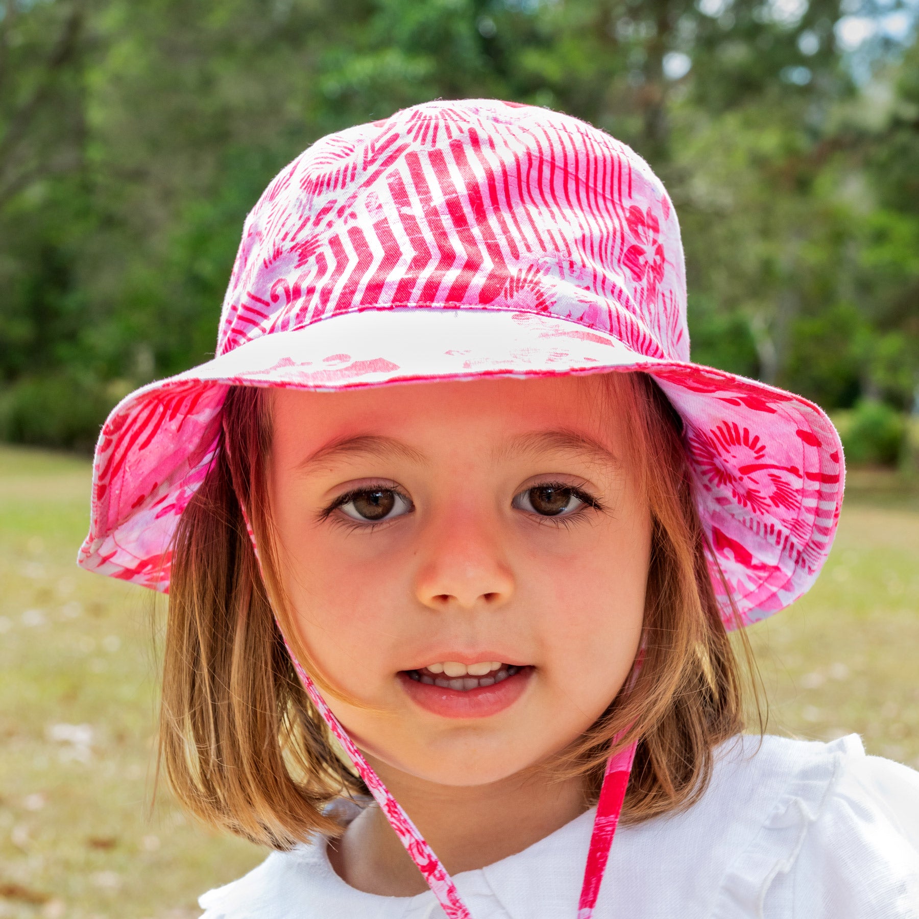 Young girl wearing a pink patterned sun hat outdoors