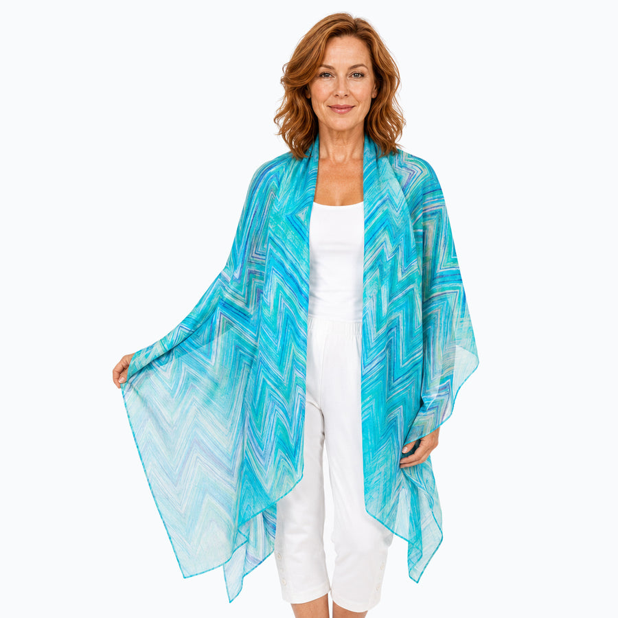 Woman wearing the Claire Powell Serenity silk scarf, draped open around the shoulders, white camisole and white capris
