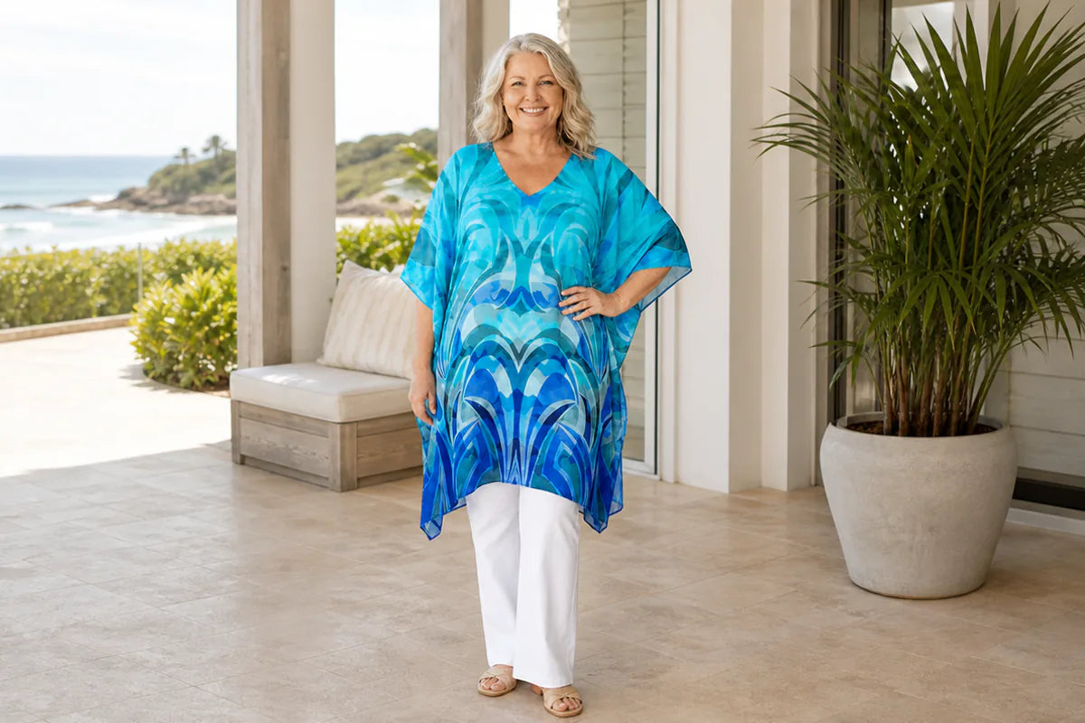 Mature plus-size model wearing the Claire Powell Waves kaftan top at a coastal resort
