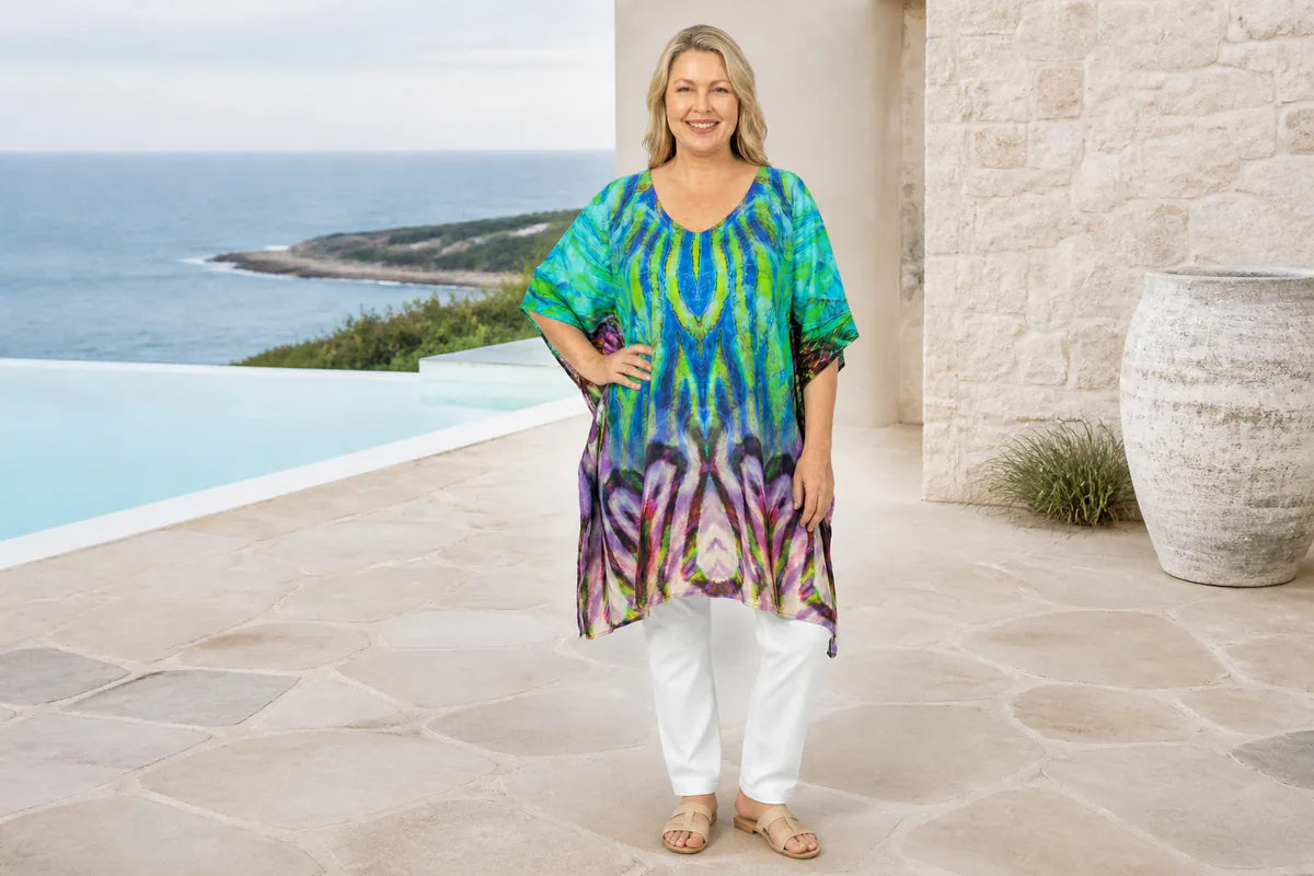 Mature plus-size model wearing the Claire Powell Cascade kaftan top at a coastal resort