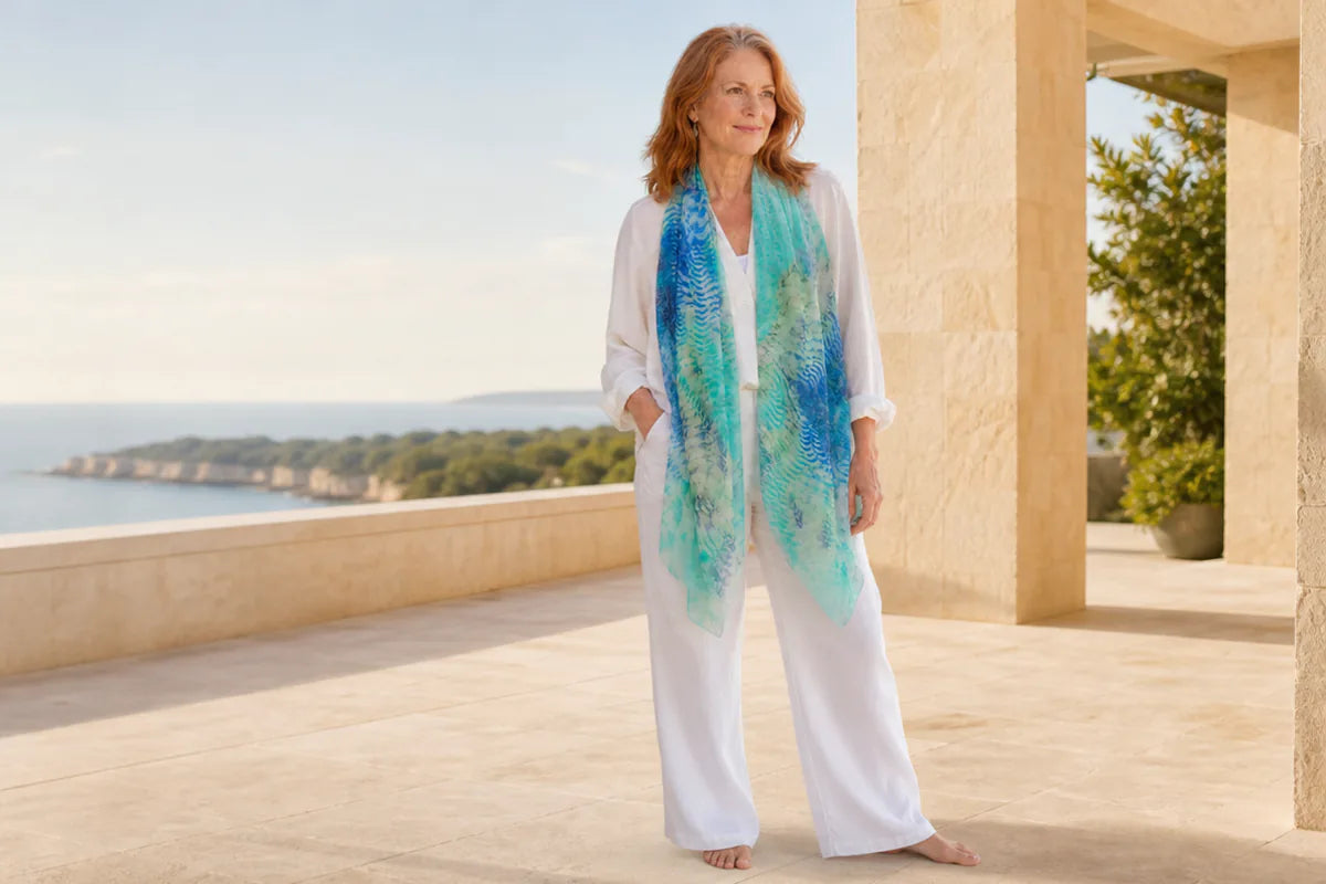 Mature model wearing the Claire Powell Marine silk-modal scarf at a coastal resort