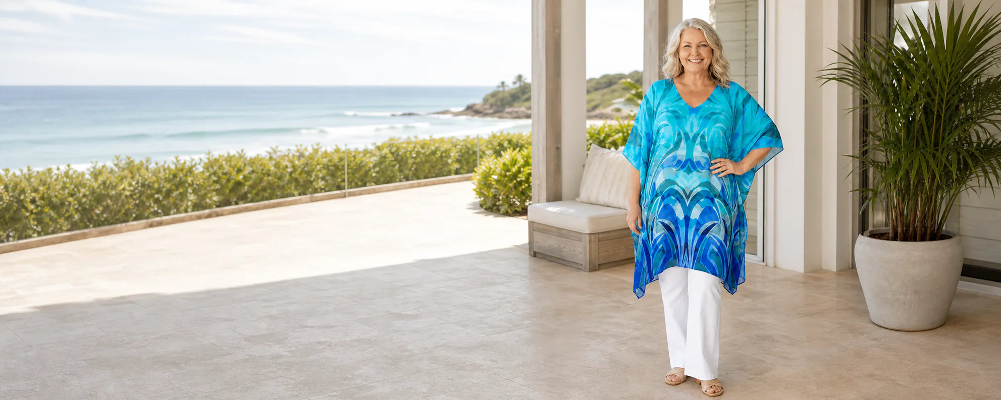Mature plus-size model wearing the Claire Powell Waves mini kaftan top at a coastal resort