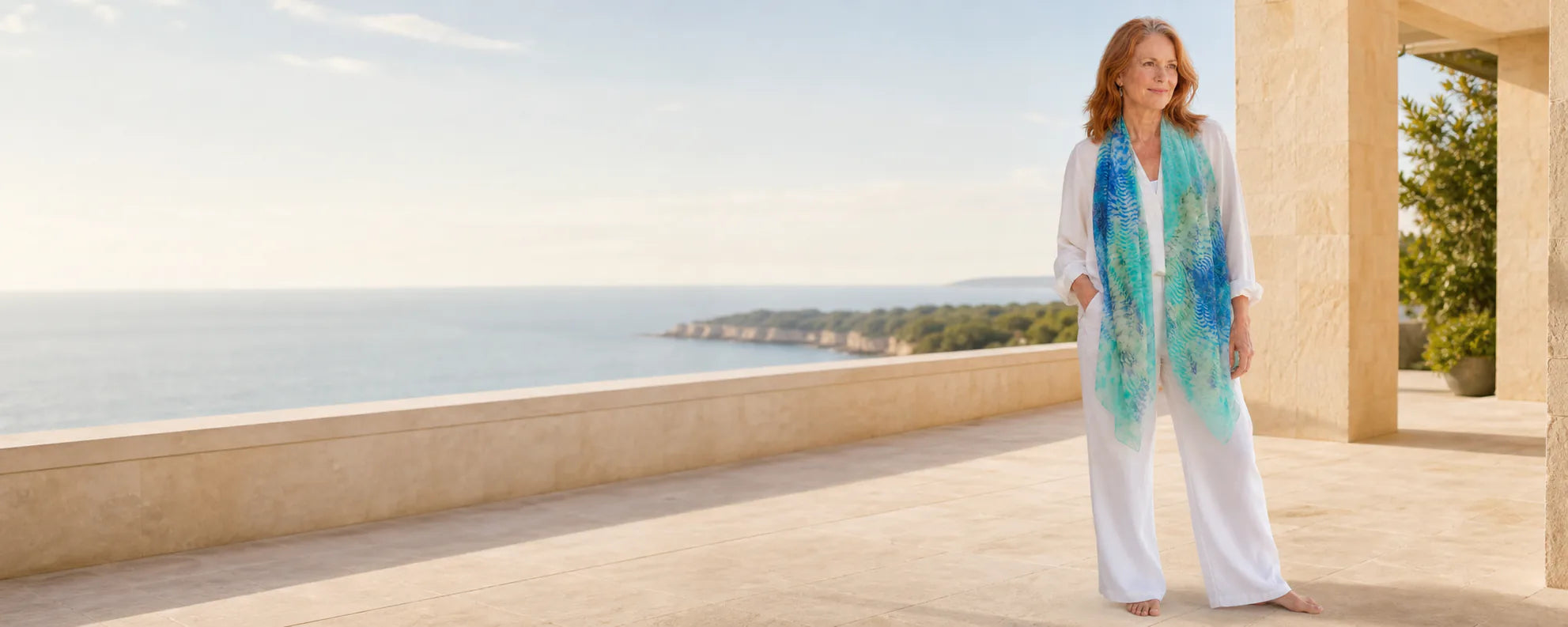 Mature model wearing the Claire Powell Marine silk-modal scarf at a coastal resort