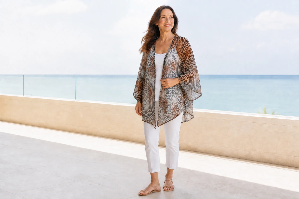 Mature model wearing the Claire Powell Jungle chiffon kimono at a coastal resort
