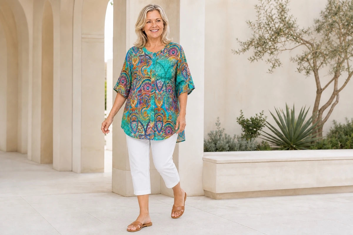 Mature model wearing the Claire Powell Mosaic A-Line Tunic Shirt with white cotton-lycra capri pants at a coastal resort